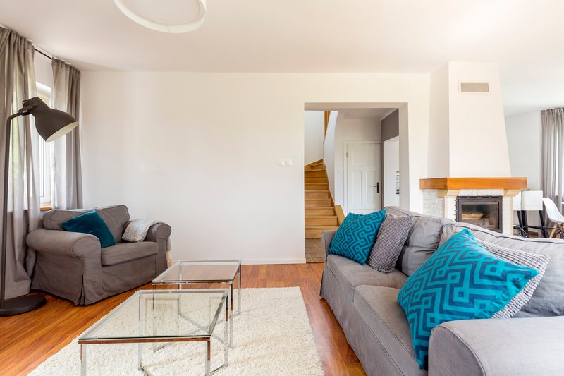 Sala de estar espaciosa con sofá modular en tono chocolate, iluminación natural abundante y vista al jardín privado.